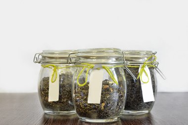 Beyaz arka plan ile ahşap tabloda çay cam kavanozlar