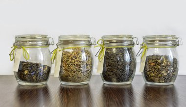 Beyaz arka plan ile ahşap tabloda çay cam kavanozlar