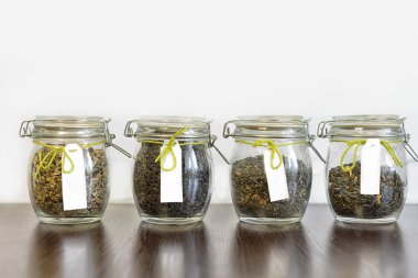 Beyaz arka plan ile ahşap tabloda çay cam kavanozlar