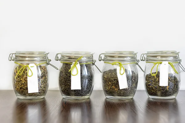 Beyaz arka plan ile ahşap tabloda çay cam kavanozlar