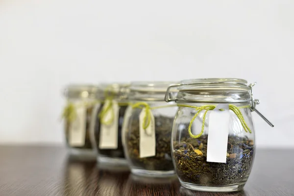 tea in glass jars on wooden table with white background