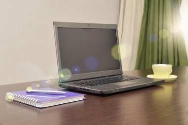 Laptop bir adres defteri, kupa ve kalem masanın üzerinde. güneş patlaması
