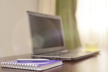 Laptop bir adres defteri, kupa ve kalem masanın üzerinde. güneş patlaması