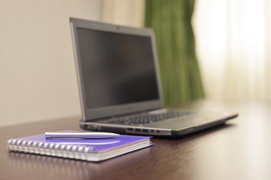 Laptop bir adres defteri ve kalem masada.