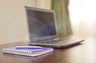 Laptop bir adres defteri ve kalem masanın üzerinde. güneş patlaması