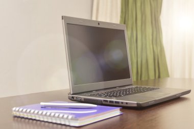 Laptop bir adres defteri ve kalem masanın üzerinde. güneş patlaması