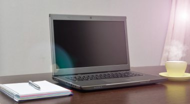 Laptop bir adres defteri, kupa ve kalem masanın üzerinde. güneş patlaması