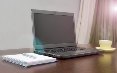 Laptop bir adres defteri, kupa ve kalem masanın üzerinde. güneş patlaması