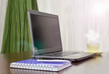 Laptop bir adres defteri, kupa ve kalem masanın üzerinde. güneş patlaması