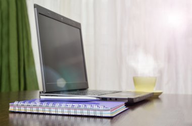 Laptop bir adres defteri, kupa ve kalem masanın üzerinde. güneş patlaması