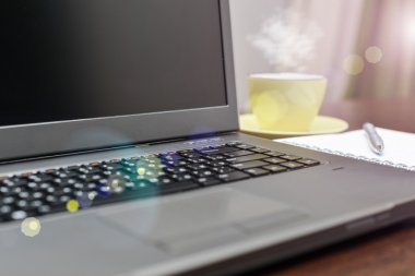 Laptop bir adres defteri, kupa ve kalem masanın üzerinde. güneş patlaması
