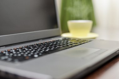 Laptop bir adres defteri, kupa ve kalem masada.