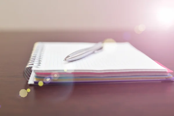 Блокнот і сталева ручка на столі з сонячним світлом — стокове фото