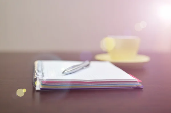 Notatnik, stalowe pióro i na stole z światło słoneczne żółty — Zdjęcie stockowe
