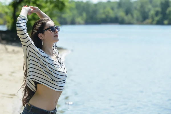 Bella ragazza sulla spiaggia guarda l'acqua — Foto Stock