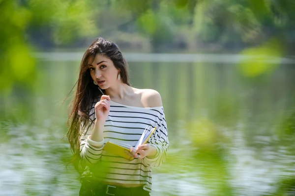 Dziewczyna z notebooka w parku, w pobliżu rzeki — Zdjęcie stockowe
