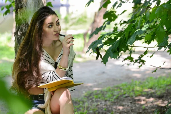 Girl with a notebook in park near the river — Stock Photo, Image