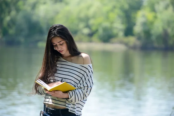 Dziewczyna z notebooka w parku, w pobliżu rzeki — Zdjęcie stockowe