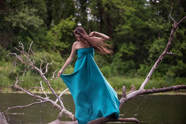 Girl wearing dress standing in river near forest — Stock Photo, Image