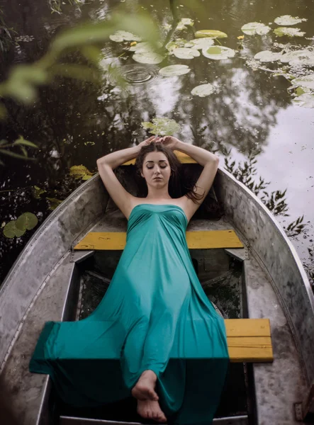 Lange Haare brünett in einem Kleid, das auf dem Boot liegt — Stockfoto