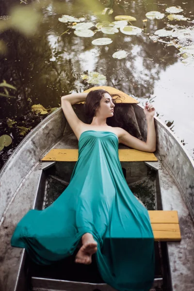 Lange Haare brünett in einem Kleid, das auf dem Boot liegt — Stockfoto