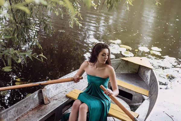 Długie włosy brunetka w sukni siedzi na łodzi — Zdjęcie stockowe