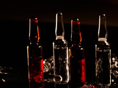 Tıbbi ampuller kapanıyor. Bir sürü ampul. Masada cam ampuller var. İlaç ile dağılmış ampuller.