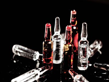 Tıbbi ampuller kapanıyor. Bir sürü ampul. Masada cam ampuller var. İlaç ile dağılmış ampuller.