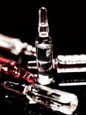 Tıbbi ampuller kapanıyor. Bir sürü ampul. Masada cam ampuller var. İlaç ile dağılmış ampuller.