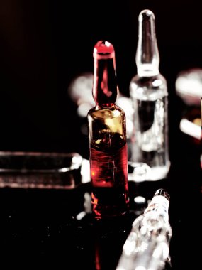 Tıbbi ampuller kapanıyor. Bir sürü ampul. Masada cam ampuller var. İlaç ile dağılmış ampuller.