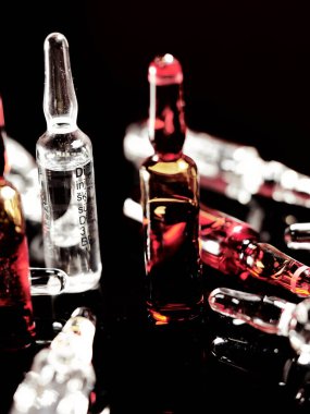 Tıbbi ampuller kapanıyor. Bir sürü ampul. Masada cam ampuller var. İlaç ile dağılmış ampuller.