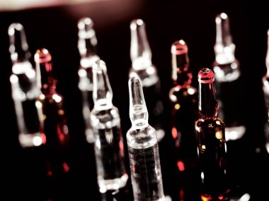 Tıbbi ampuller kapanıyor. Bir sürü ampul. Masada cam ampuller var. İlaç ile dağılmış ampuller.