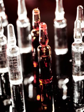 Tıbbi ampuller kapanıyor. Bir sürü ampul. Masada cam ampuller var. İlaç ile dağılmış ampuller.