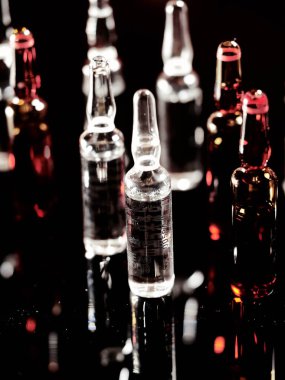 Tıbbi ampuller kapanıyor. Bir sürü ampul. Masada cam ampuller var. İlaç ile dağılmış ampuller.