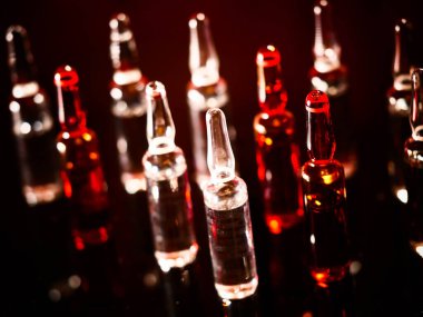 Tıbbi ampuller kapanıyor. Bir sürü ampul. Masada cam ampuller var. İlaç ile dağılmış ampuller.