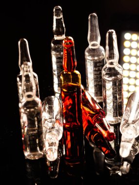 Tıbbi ampuller kapanıyor. Bir sürü ampul. Masada cam ampuller var. İlaç ile dağılmış ampuller.