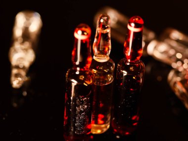 Tıbbi ampuller kapanıyor. Bir sürü ampul. Masada cam ampuller var. İlaç ile dağılmış ampuller.