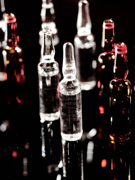 Tıbbi ampuller kapanıyor. Bir sürü ampul. Masada cam ampuller var. İlaç ile dağılmış ampuller.