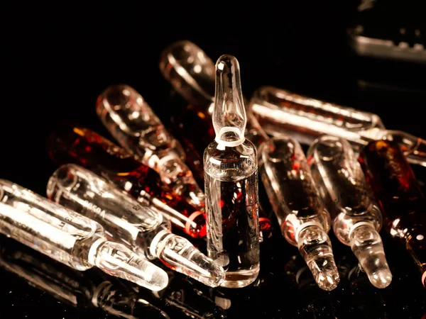 Tıbbi ampuller kapanıyor. Bir sürü ampul. Masada cam ampuller var. İlaç ile dağılmış ampuller.