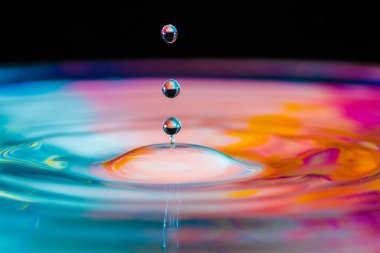 Renkli su damlası, daire şeklinde dalgalar, biraz su, yakın plan..