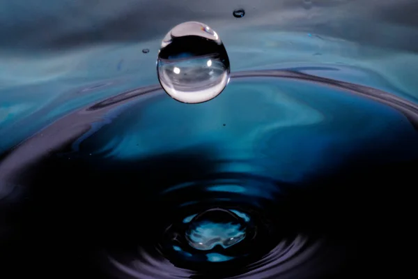 Colored water drop, circle ripples, splash of water, closeup.