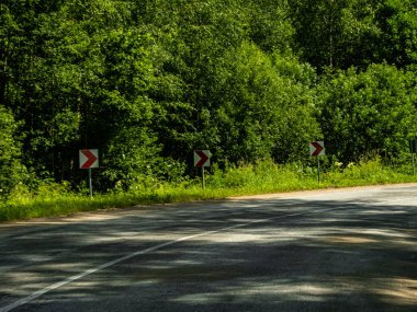 Asfalt karayolu çevresi orman, yol işareti, kara taşımacılığı ve seyahat arka planıyla çevrili.
