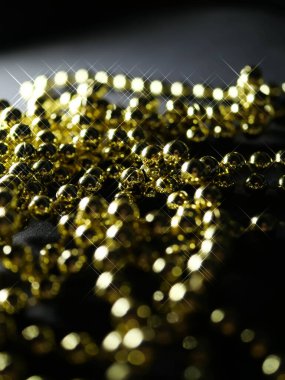 İnciler. Koyu bir arkaplanda, koyu bir masada altın gümüş inci boncuklar.