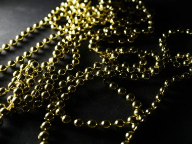 İnciler. Koyu bir arkaplanda, koyu bir masada altın gümüş inci boncuklar.