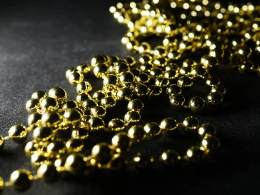 İnciler. Koyu bir arkaplanda, koyu bir masada altın gümüş inci boncuklar.