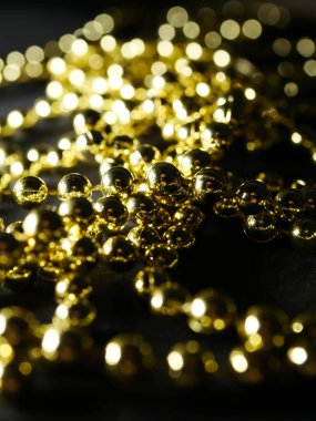 İnciler. Koyu bir arkaplanda, koyu bir masada altın gümüş inci boncuklar.