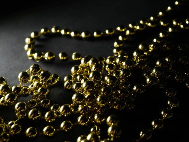 İnciler. Koyu bir arkaplanda, koyu bir masada altın gümüş inci boncuklar.