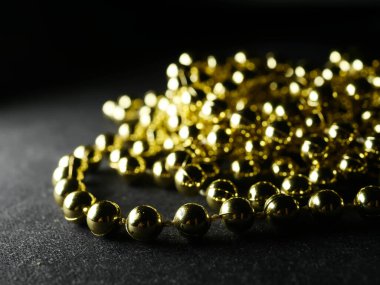 İnciler. Koyu bir arkaplanda, koyu bir masada altın gümüş inci boncuklar.