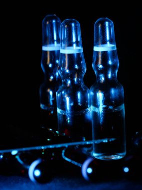 Tıbbi ampuller kapanıyor. Bir sürü ampul. Masada cam ampuller var. İlaç ile dağılmış ampuller.