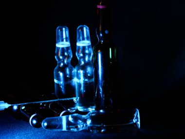 Tıbbi ampuller kapanıyor. Bir sürü ampul. Masada cam ampuller var. İlaç ile dağılmış ampuller.